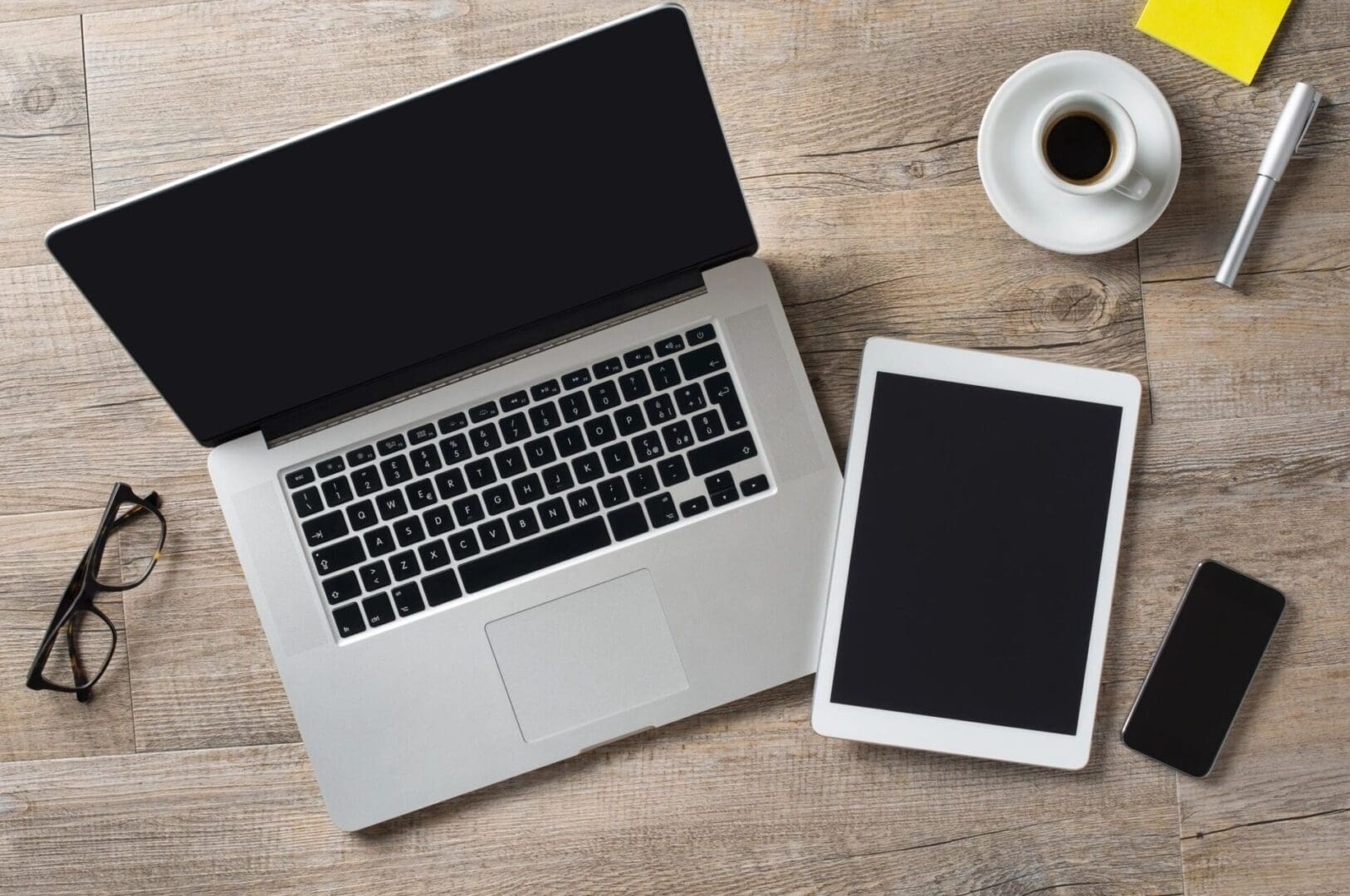 A laptop and tablet sitting on top of a wooden table.