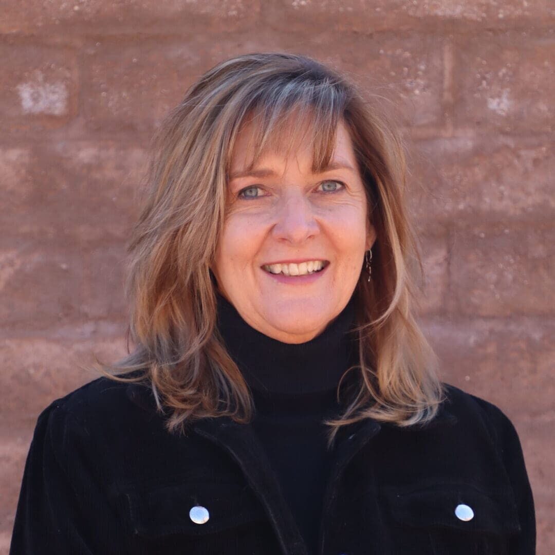 A woman in black jacket smiling for the camera.