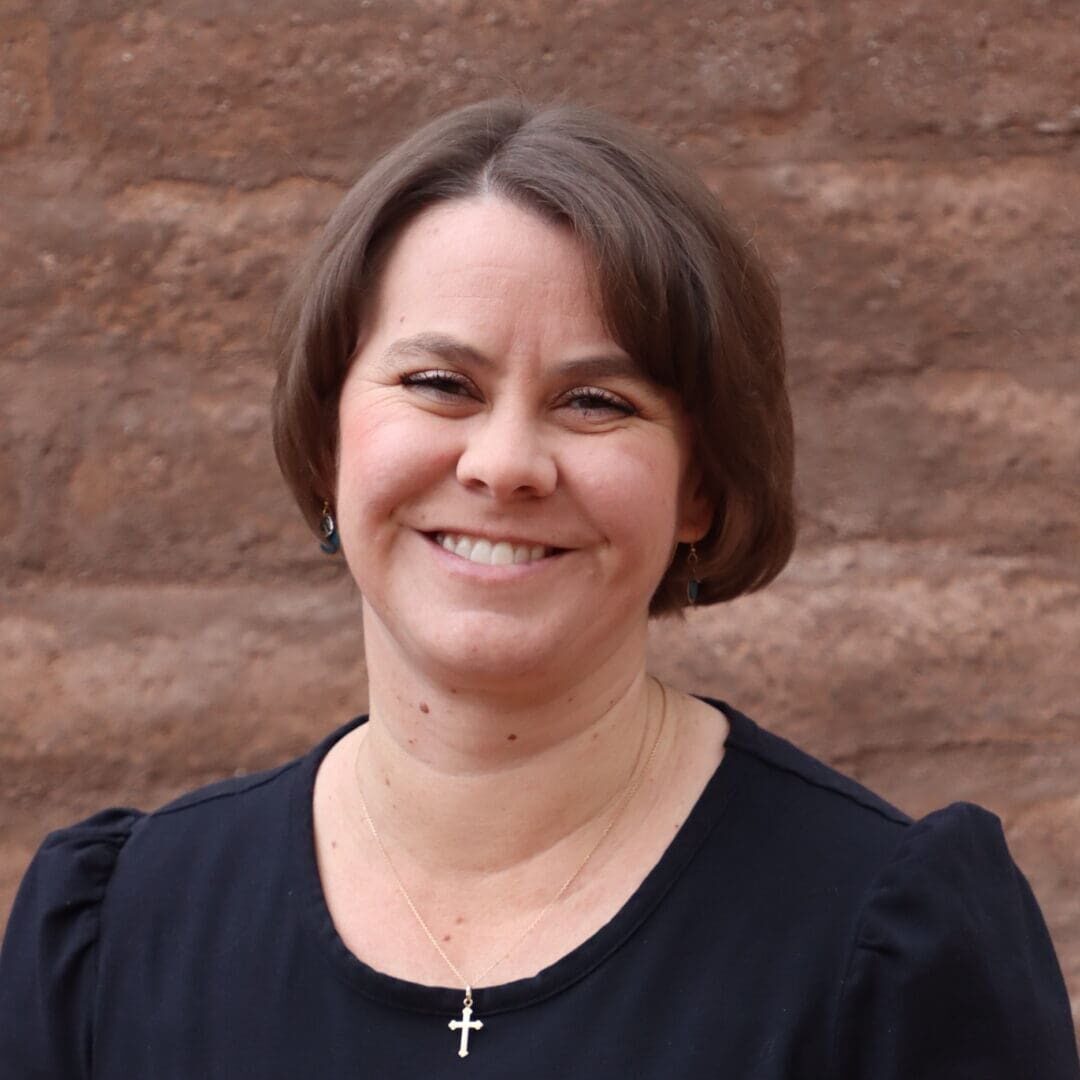 A woman standing in front of a brick wall.