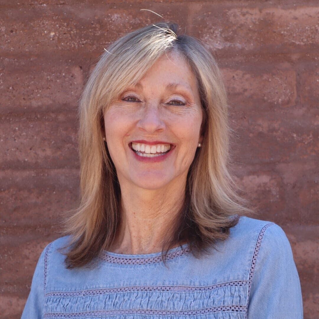 A woman standing in front of a brick wall.