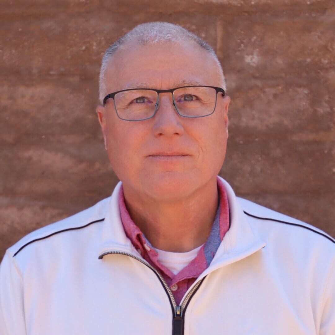 A man with glasses and a white jacket