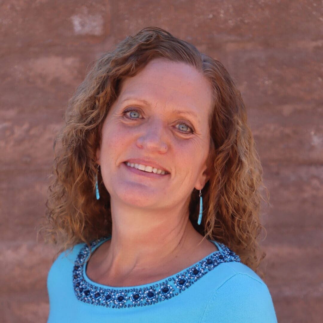 A woman with long hair and blue shirt smiling.