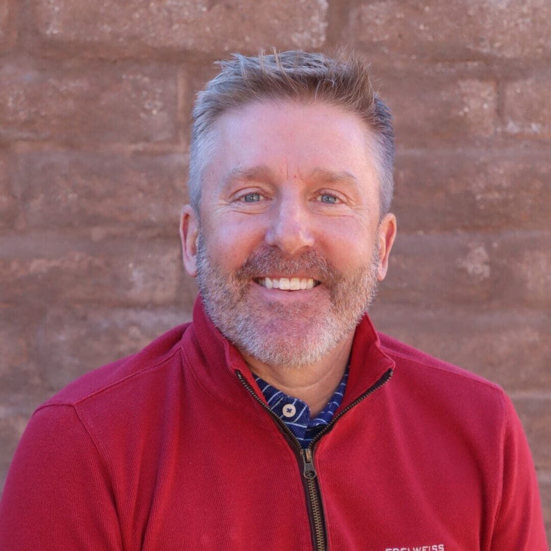 A man in red jacket smiling for the camera.